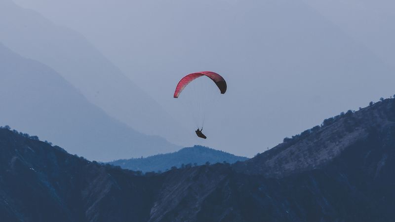 滑翔伞在雾中山间御风飞行的4K壁纸
